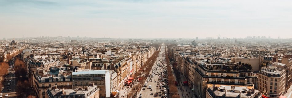 View of the Avenue des Champs-Élysées in Paris, France, with elegant architecture, bustling traffic, and the Arc de Triomphe in the distance.