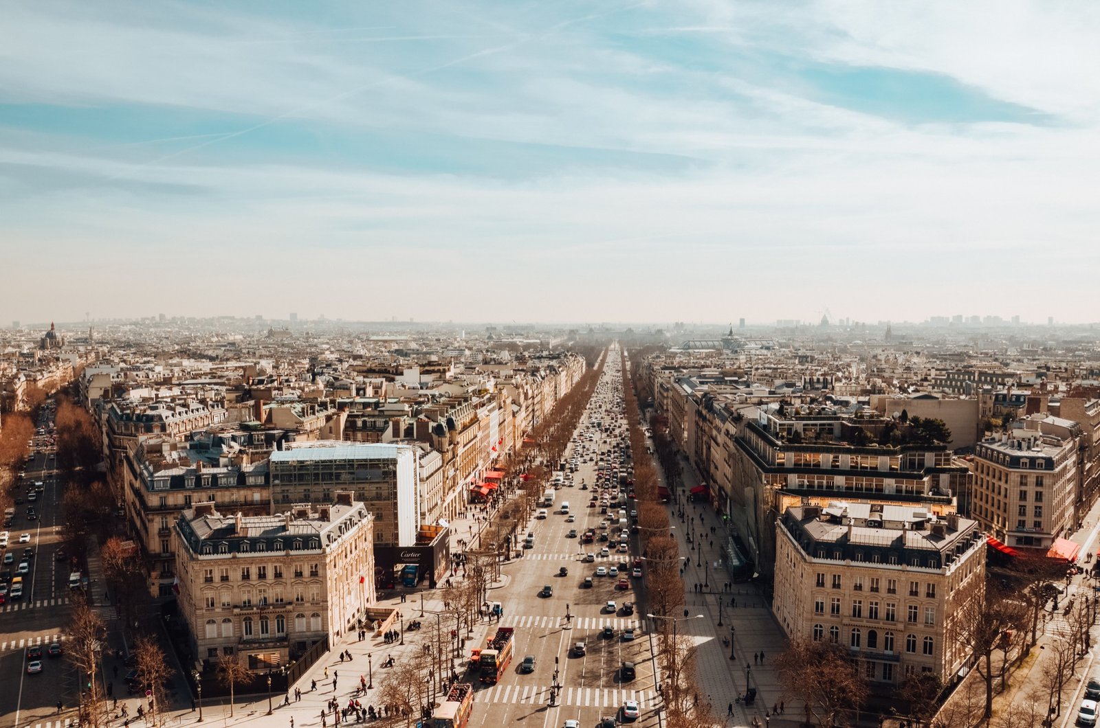 View of the Avenue des Champs-Élysées in Paris, France, with elegant architecture, bustling traffic, and the Arc de Triomphe in the distance.