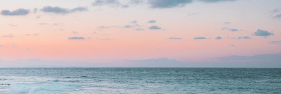 Peaceful sunset at a tropical beach in Honolulu 🇺🇸 with soft pastel skies and gentle waves rolling onto the sandy shore — a dreamy destination for travelers seeking tranquility and natural beauty in the USA.