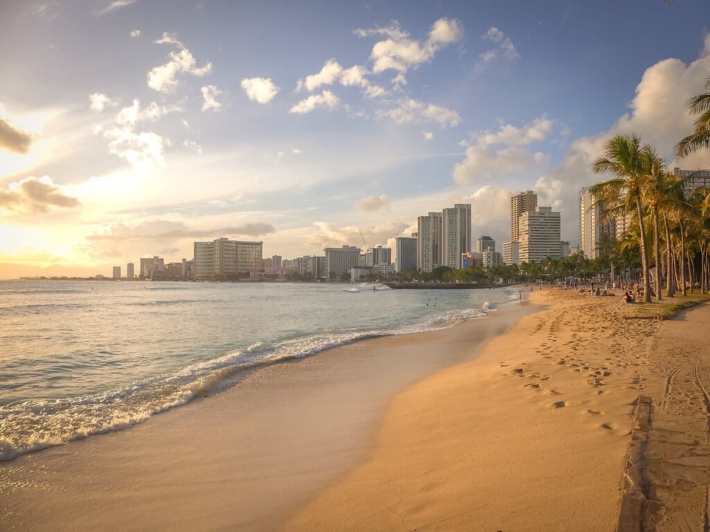 Sunset view of Waikiki Beach in Honolulu, Hawaii 🇺🇸, with golden sand, palm trees, and the city skyline in the background – a perfect tropical escape for travelers visiting one of the most beautiful cities in the USA.