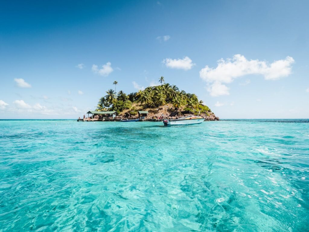 Aerial view of San Andrés beach in Colombia with vibrant turquoise sea, white sand, and coconut trees lining the shore.