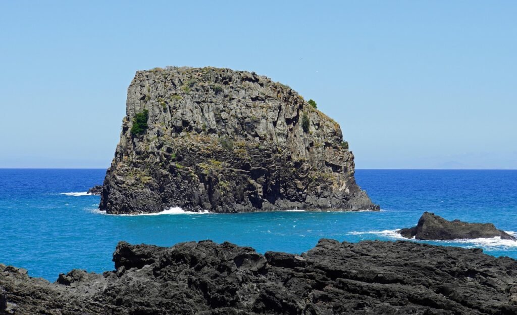 Dramatic coastal cliffs in Madeira, Portugal, with waves crashing against the rocky shore under a cloudy sky.