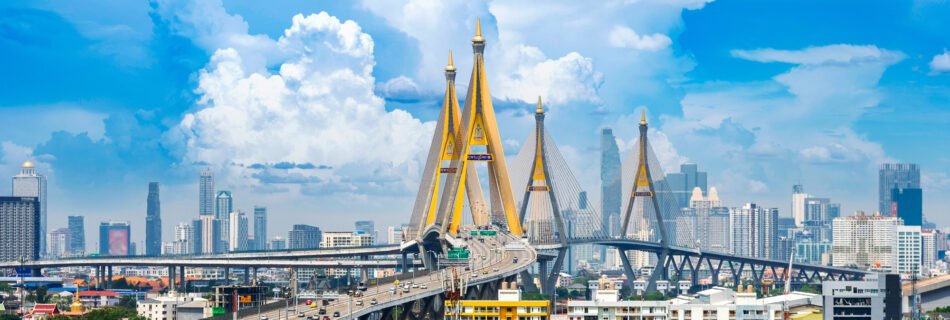 Panoramic view of the Bhumibol Bridge with the modern skyline of Bangkok in the background, showcasing the city's blend of urban infrastructure and traditional architecture.