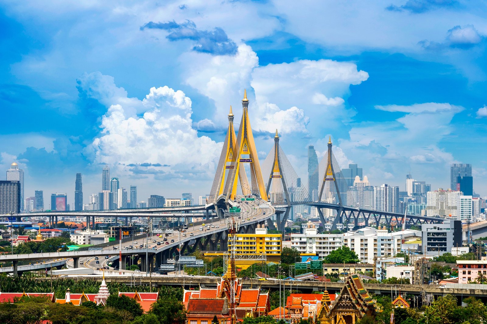 Panoramic view of the Bhumibol Bridge with the modern skyline of Bangkok in the background, showcasing the city's blend of urban infrastructure and traditional architecture.